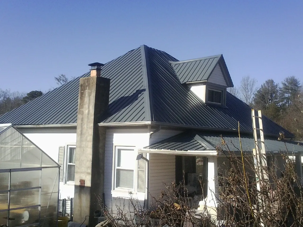 Dark blue standing seam metal roof on a white farmhouse with dormer — Slate & Tile Roof Repair by Roofing Brothers in Bartlett