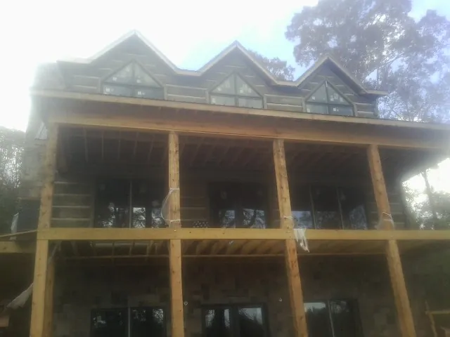 Dormers and porch framing on a large log home under construction — Roof Coating work by our crew in Bartlett