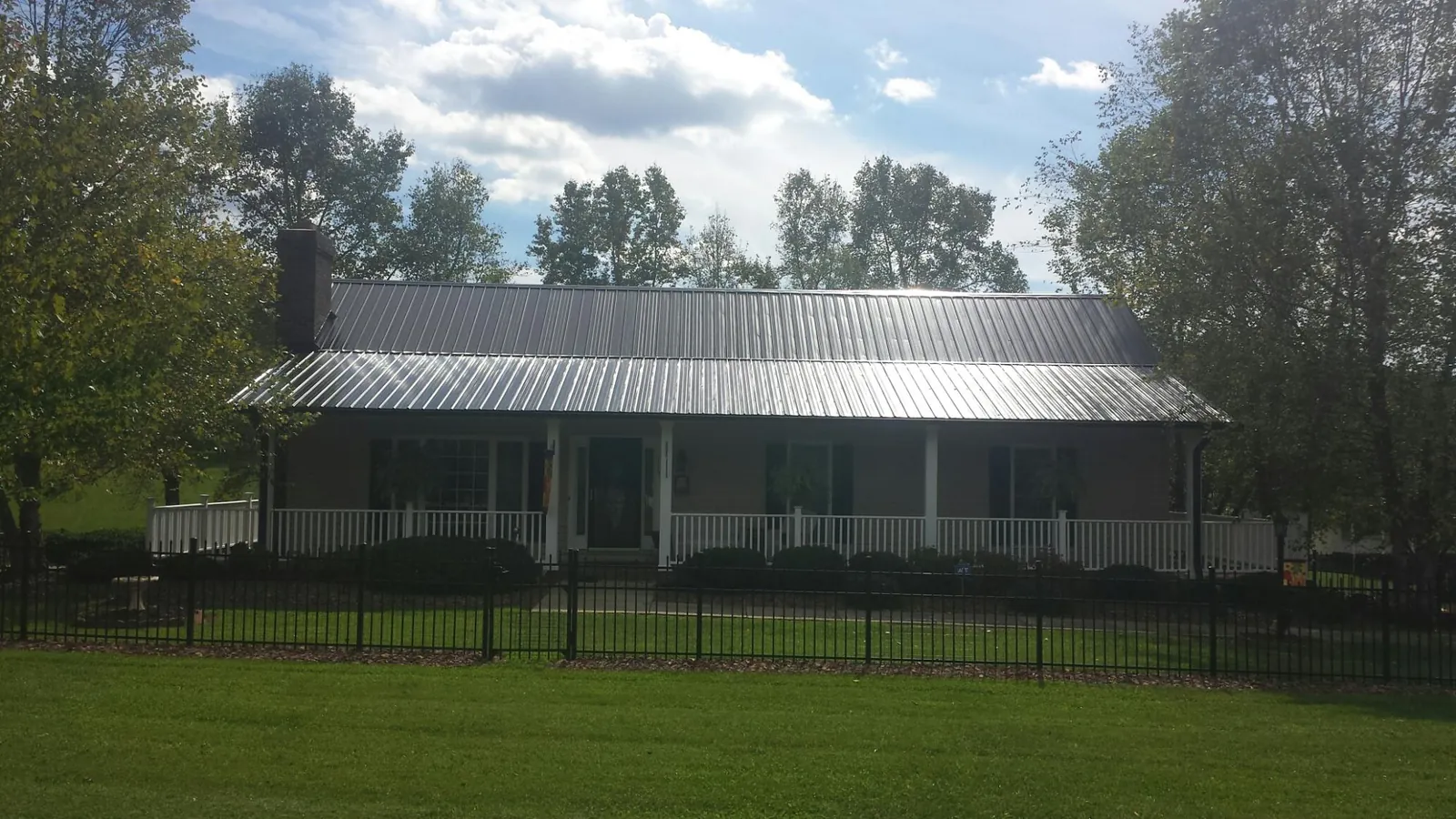 Gray metal roof on a brick ranch with a full width front porch — Gutter Guard Installation work by our crew in Bartlett